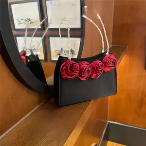 Detailed shot of vintage black bag with silk red roses and pearl beaded handle