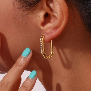 Close-up of a gold-plated U-shaped earring featuring zircon stones on a model