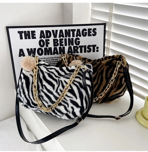 Detail of plush zebra print tote bag with golden thick chain and fluffy pompom charm