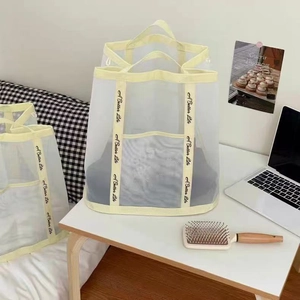 Close-up of cream white mesh storage bags with A Better Life printed yellow handles