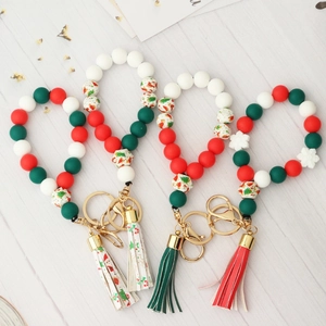 Christmas silicone bead bracelet with tassels and festive charms on wooden background