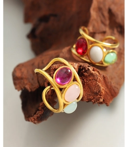 Macro detail of 18K gold plated vintage rings with colorful oval gemstones on wood