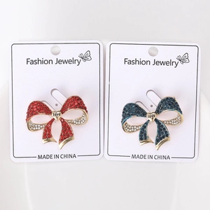 Bowtie brooches with red and blue rhinestones and gold heart detail on jewelry card