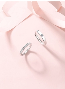 Close-up of S925 sterling silver couple rings with sparkling pavé diamonds on pink background
