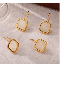 Detailed view of square cream resin earrings with polished gold-plated stainless steel frames