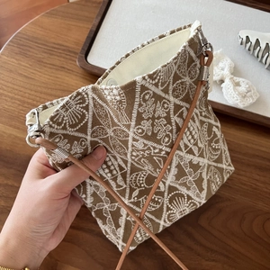 Detailed embroidery and leather strap on a vintage brown canvas crossbody phone bag
