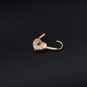 Macro detail of a gold heart padlock earring with clear cubic zirconia stones