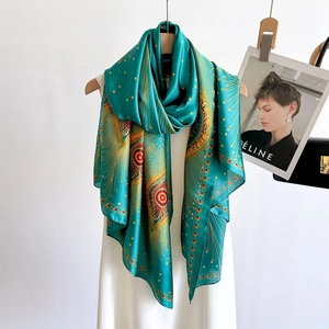 Elegant green silk scarf with golden peacock feather prints displayed on a white hanger