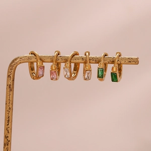 Détail de créoles plaquées or avec zircons rectangulaires roses, blancs et verts
