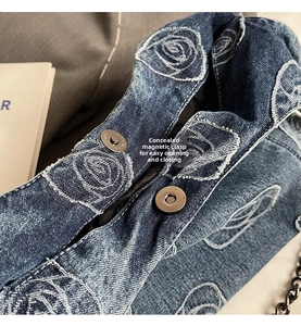 Macro detail of denim shoulder bag with white rose print and invisible magnetic closure