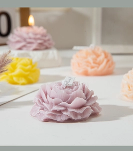 Dettaglio di candele profumate a forma di peonia in viola e colori pastello tenui