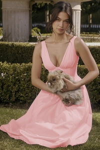 Detailed view of pink deep V-neck sundress featuring pleated waist in a lush garden setting