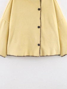 Detail of cream woolen coat showing contrast brown stitching and black round buttons