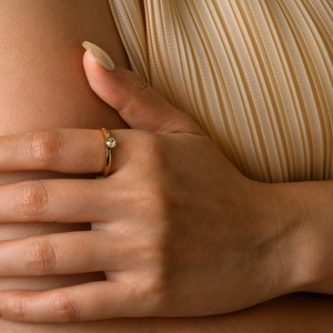 Close-up of elegant gold plated ring with round clear zircon on model's finger