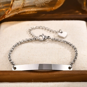 Macro shot of silver stainless steel chain bracelet with blank ID plate and heart charm