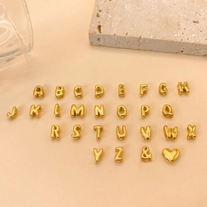 Macro view of 26 golden 3D bubble alphabet beads with heart and ampersand symbols