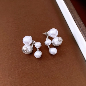 Detail of silver drop earrings featuring multi-size white pearls and relief engraving