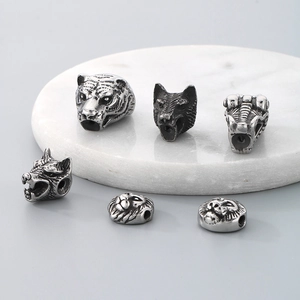 Detailed view of six vintage silver animal head beads in wolf and lion styles on marble