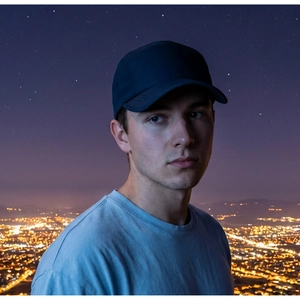 Close-up of a navy blue 5-panel baseball cap on a model with city night lights background