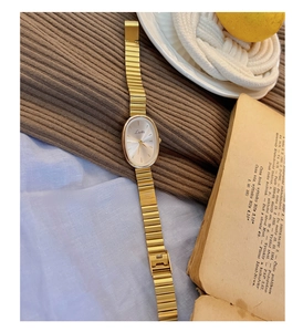 Detailed macro view of an oval vintage gold quartz watch on a cozy textured fabric
