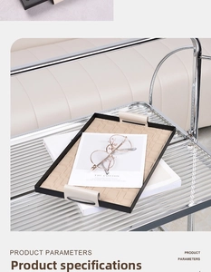 Detail of woven beige texture on a black metal tray with elegant leather handles
