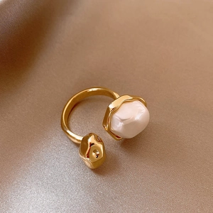 Macro shot of vintage gold-plated open ring with irregular pearls on champagne silk