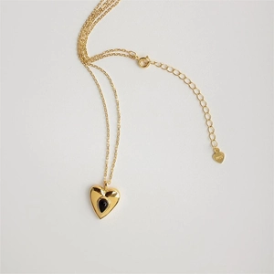 Macro detail of 925 silver heart necklace with black drop pendant and gold plating