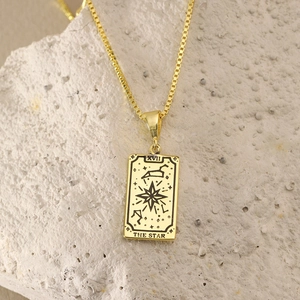 Detail view of 18K gold tarot card necklace featuring The Star engraving on textured stone