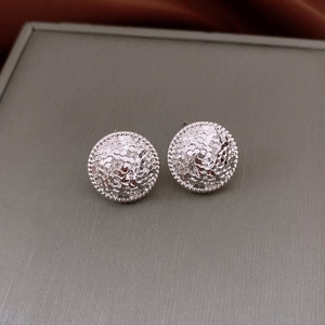 Vue détaillée de boucles d'oreilles sphériques argentées avec surface martelée texturée