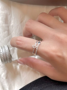 Detail of silver double-layer fish ring worn by model with minimalist bead accents