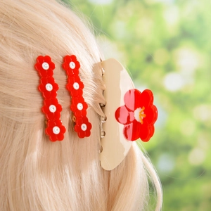 Vue détaillée d'un ensemble de 3 pinces à cheveux à fleurs rouges sur cheveux