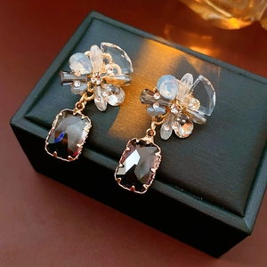 Macro shot of silver needle floral earrings with grey rectangular stones and blue petals