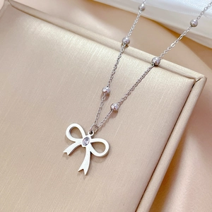 Detail of silver bow pendant with zircon stone on bead chain in jewelry box