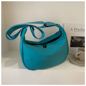 Detail of teal nylon crescent bag showing the adjustable strap and double zipper closure