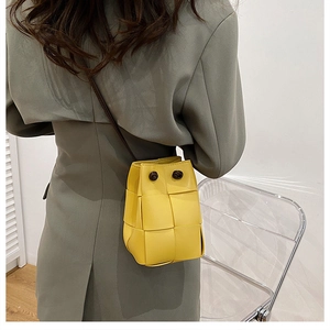 Detailed view of yellow hand-woven bucket bag with wide strap knots on model back
