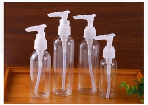 Detailed close-up of various sizes of clear PET lotion pump bottles on a wooden tray