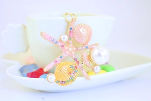 Detailed view of starfish and seashell keychain with pearls and crystals in a teacup