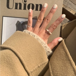 Close-up of silver heart-shaped ring and pearl ring on hand with warm autumn vibe