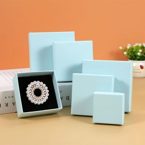Tiered stack of light blue jewelry boxes with black flocking lining for brooches