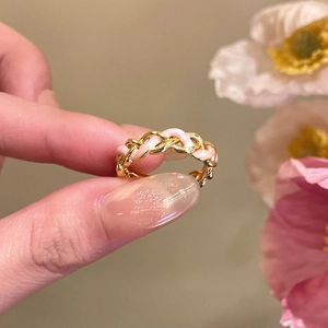 Detail of 18k gold plated woven ring featuring pink enamel floral texture and zircon