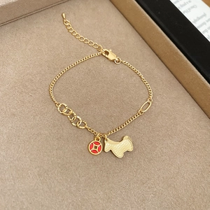 Detail of gold charm bracelet with red enamel coin and animal pendant on jewelry tray