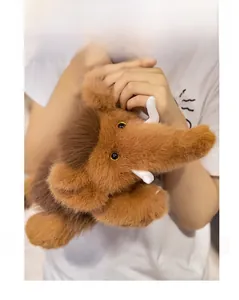 Detailed close-up of a soft plush mammoth toy with long brown fur and white tusks