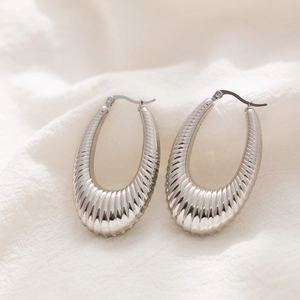 Macro detail of silver stainless steel teardrop hoop earrings with radiant pleated texture