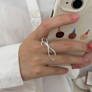 Close-up of minimalist silver bow ring worn by a model in a trendy lifestyle shot