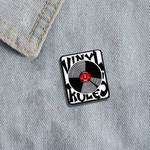 Retro vinyl record enamel pin with Vinyl Rules text on a blue denim jacket background