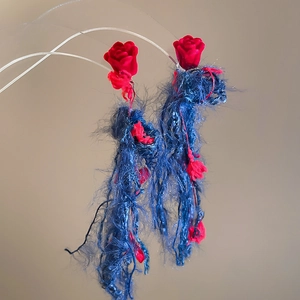 Dettaglio della rosa di velluto rosso e nappe di lana blu con boccioli di fiori micro