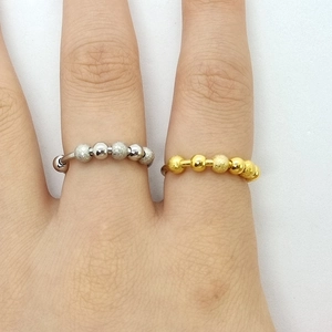 Detail view of gold and silver rotating bead anxiety rings on model fingers