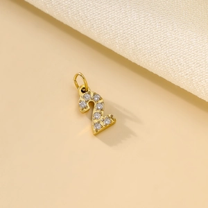 Macro shot of gold number 2 pendant with sparkling crystals on a textured fabric base