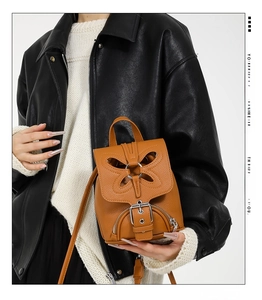 Gros plan du mini sac à dos en cuir marron avec design papillon et boucle métallique
