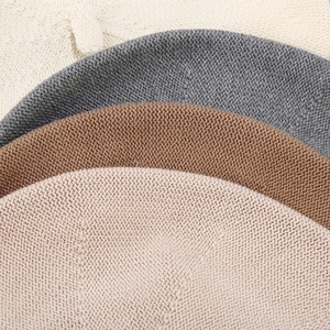 Close-up of four knitted cotton berets in beige, grey, caramel, and khaki showing textures